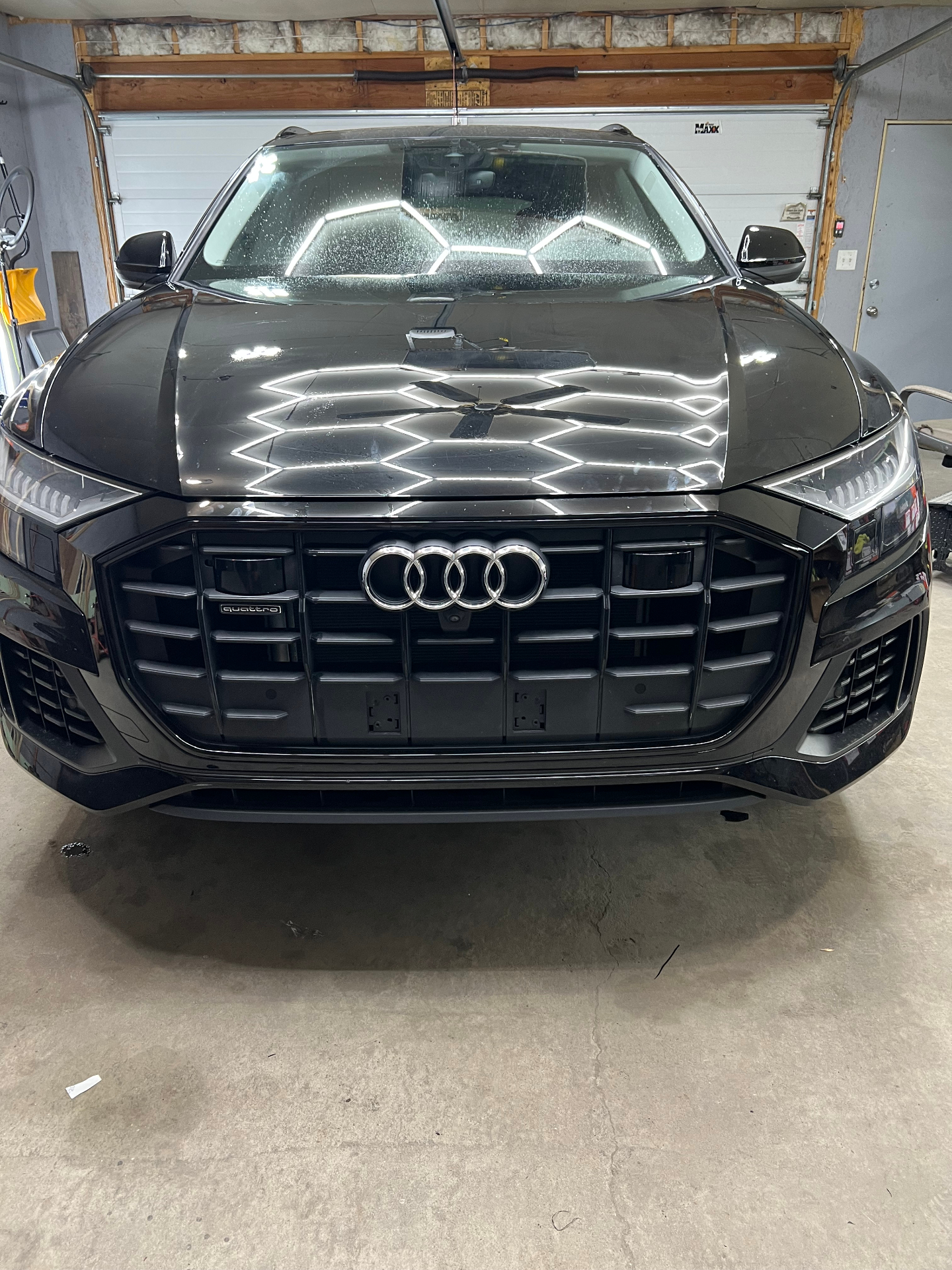 Gloss black Audi front end with crisp shop reflections.
